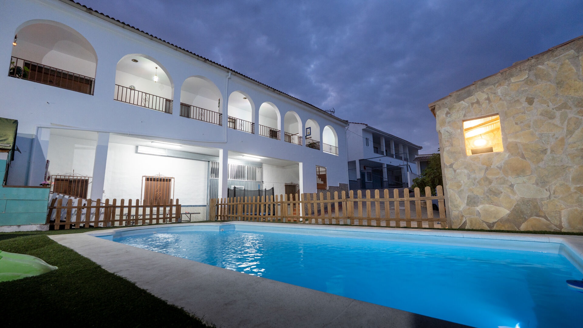 Piscina privada nocturna con tobogán y zona de descanso